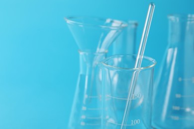 Photo of Different laboratory glassware on light blue background, closeup. Space for text