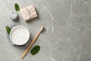 Flat lay composition with tooth powder and mint on light grey marble table, space for text