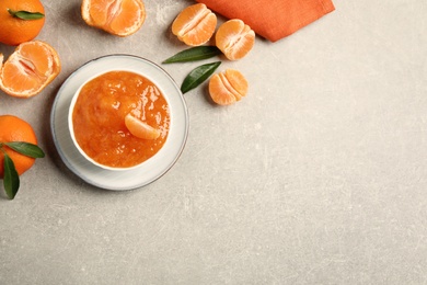 Flat lay composition with delicious tangerine jam on light grey table. Space for text