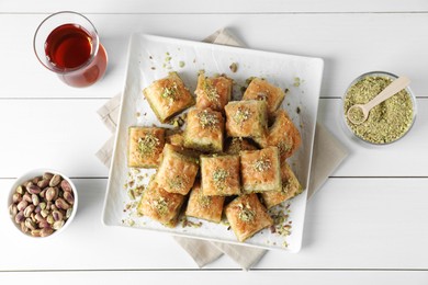 Delicious fresh baklava with chopped nuts served on white wooden table, flat lay. Eastern sweets