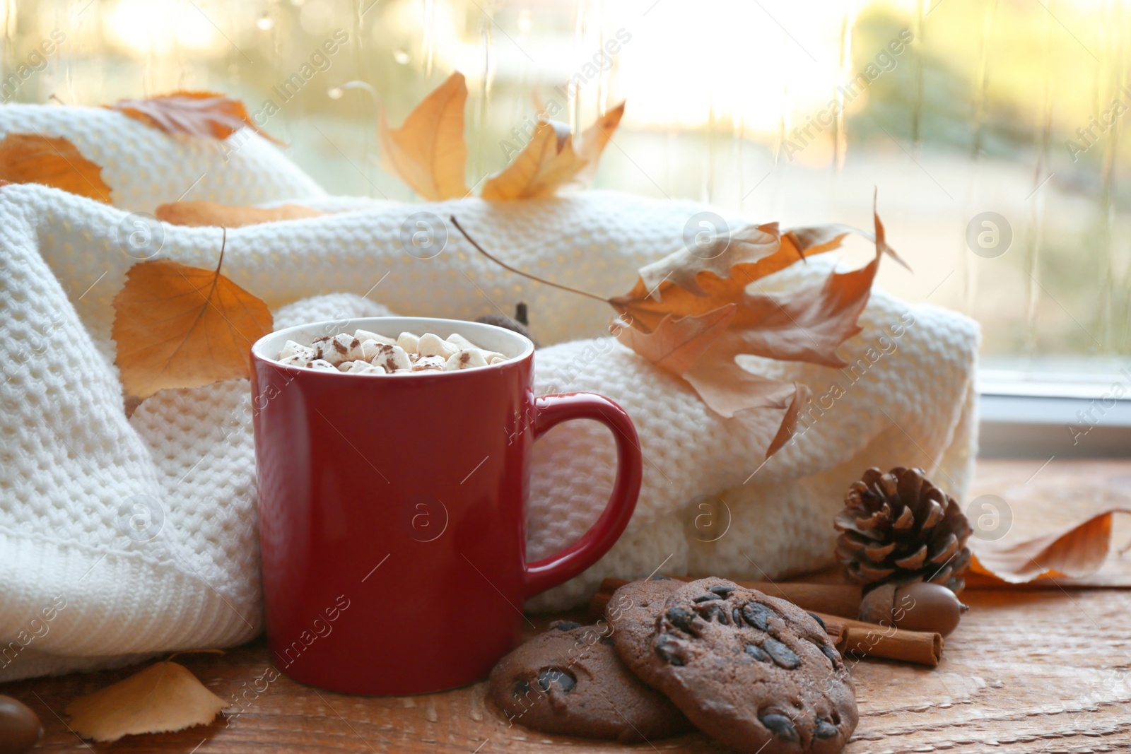 Photo of Composition with cup of hot drink, sweater and autumn leaves on windowsill. Cozy atmosphere