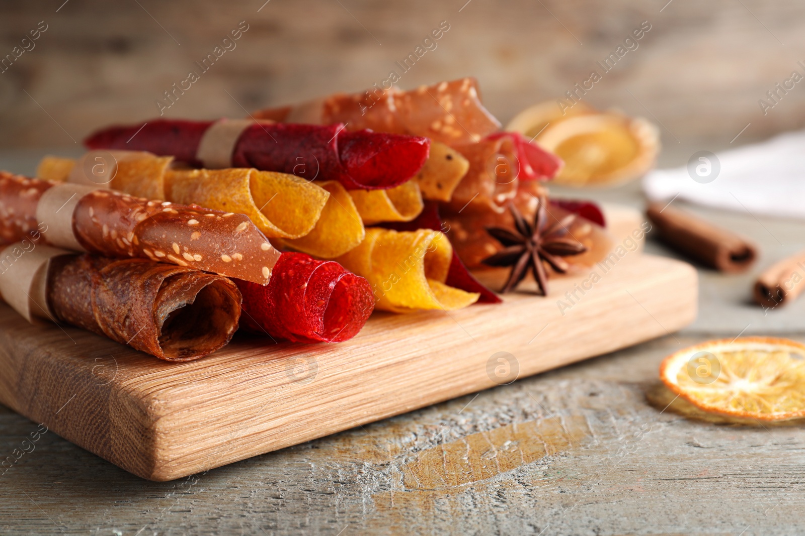 Photo of Delicious fruit leather rolls on wooden table, closeup