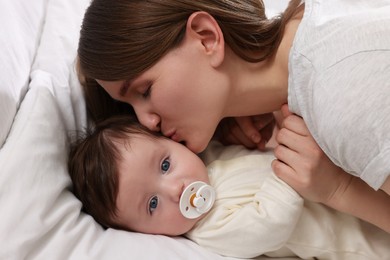 Photo of Happy mother kissing her little baby on bed