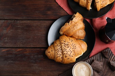 Flat lay composition with tasty croissants, chocolate and coffee on wooden table. Space for text