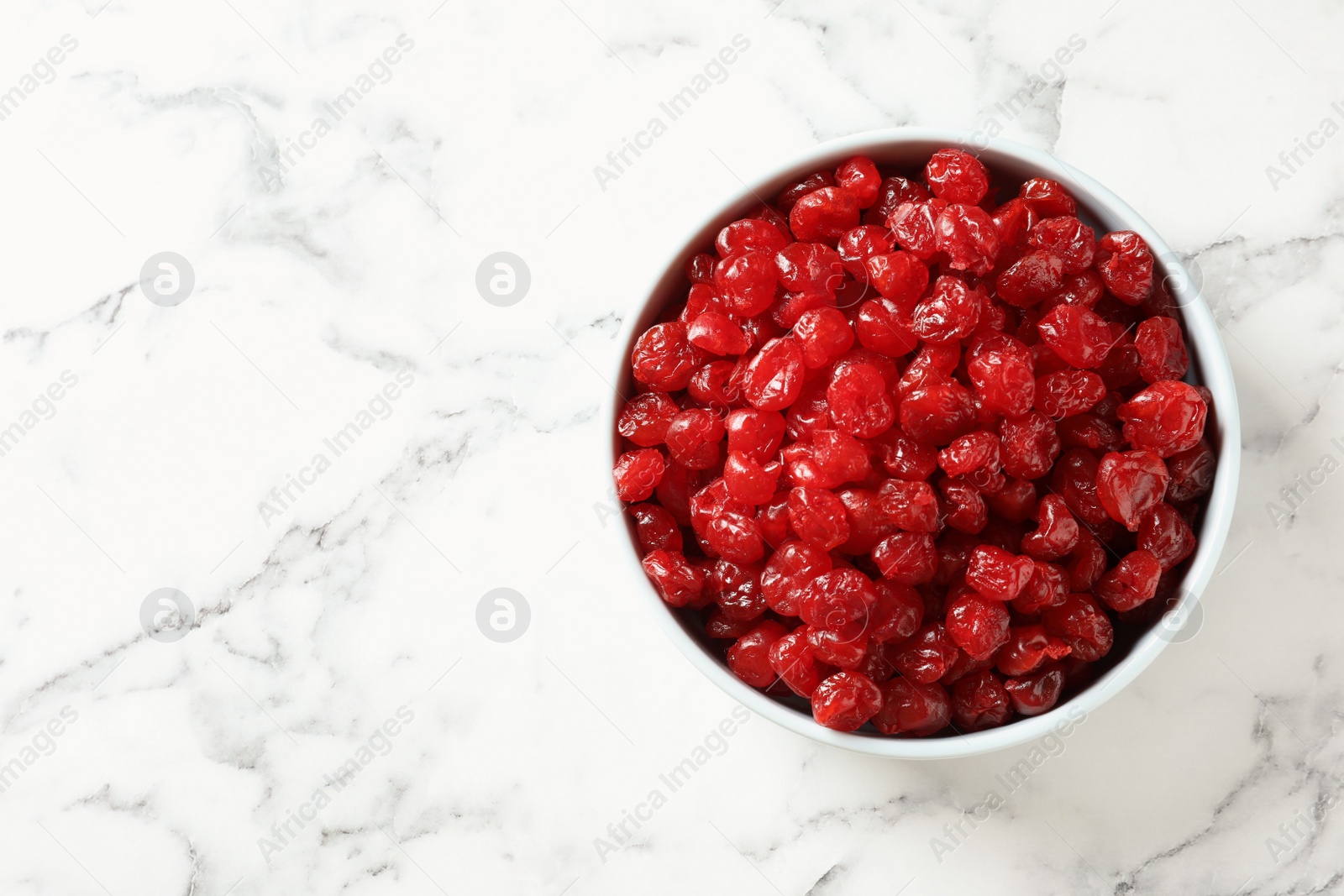 Photo of Bowl of sweet cherries on marble background, top view with space for text. Dried fruit as healthy snack