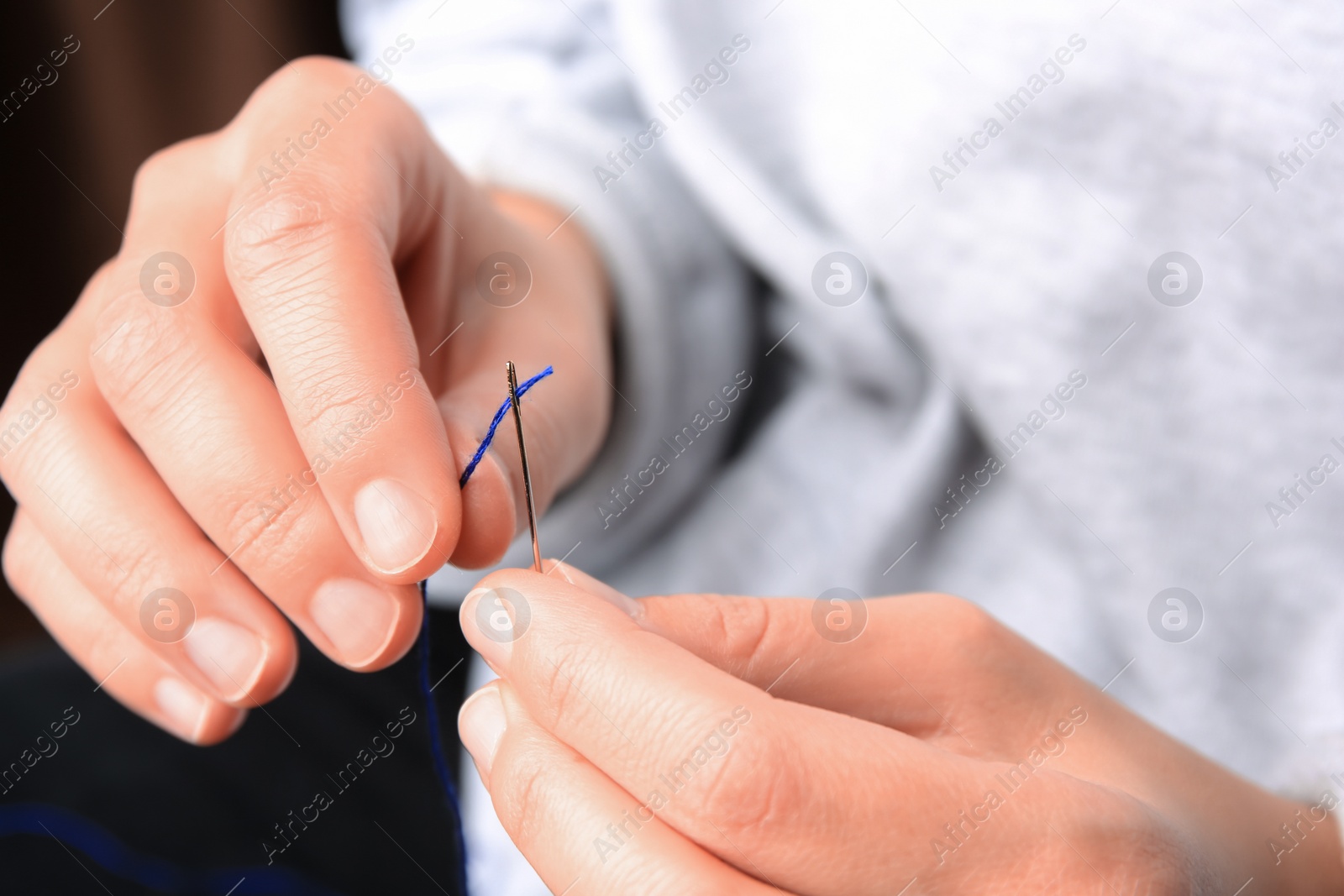 Photo of Closeup view of woman threading sewing needle