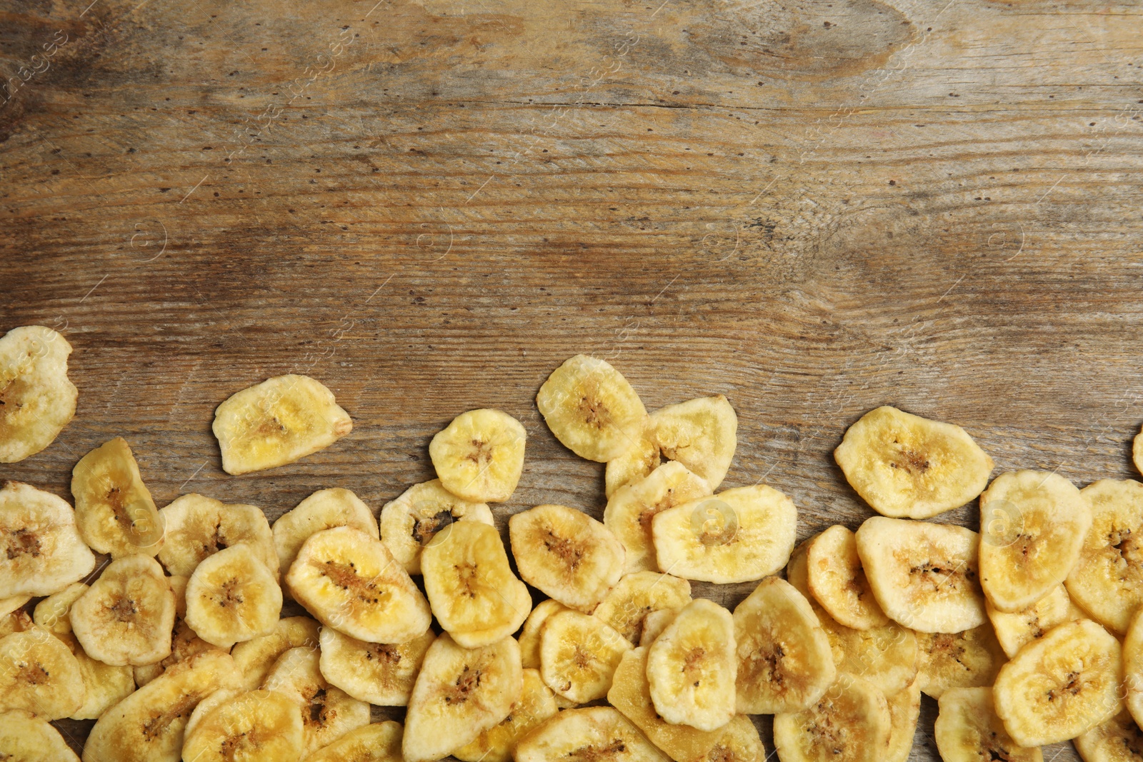 Photo of Tasty banana slices on wooden background, top view with space for text. Dried fruit as healthy snack