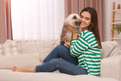 Woman with her cute cat on soft sofa at home