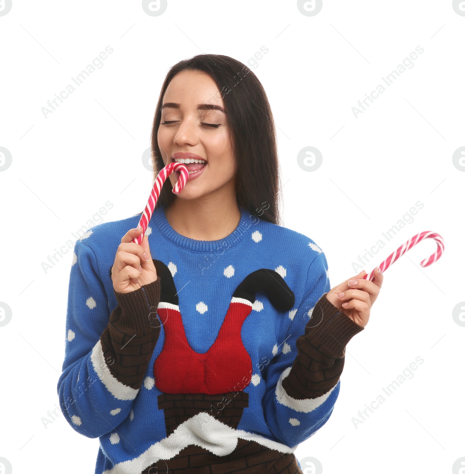 Photo of Young woman in Christmas sweater eating candy canes on white background