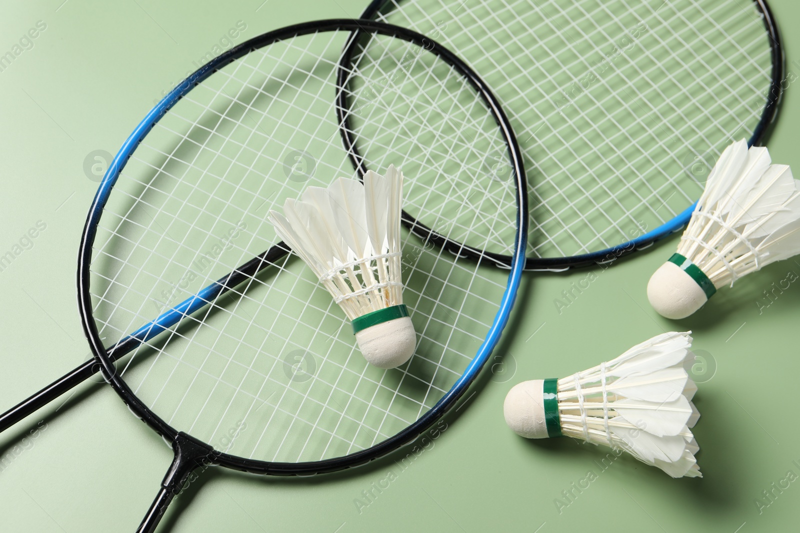 Photo of Feather badminton shuttlecocks and rackets on green background, above view