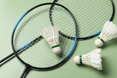 Feather badminton shuttlecocks and rackets on green background, above view