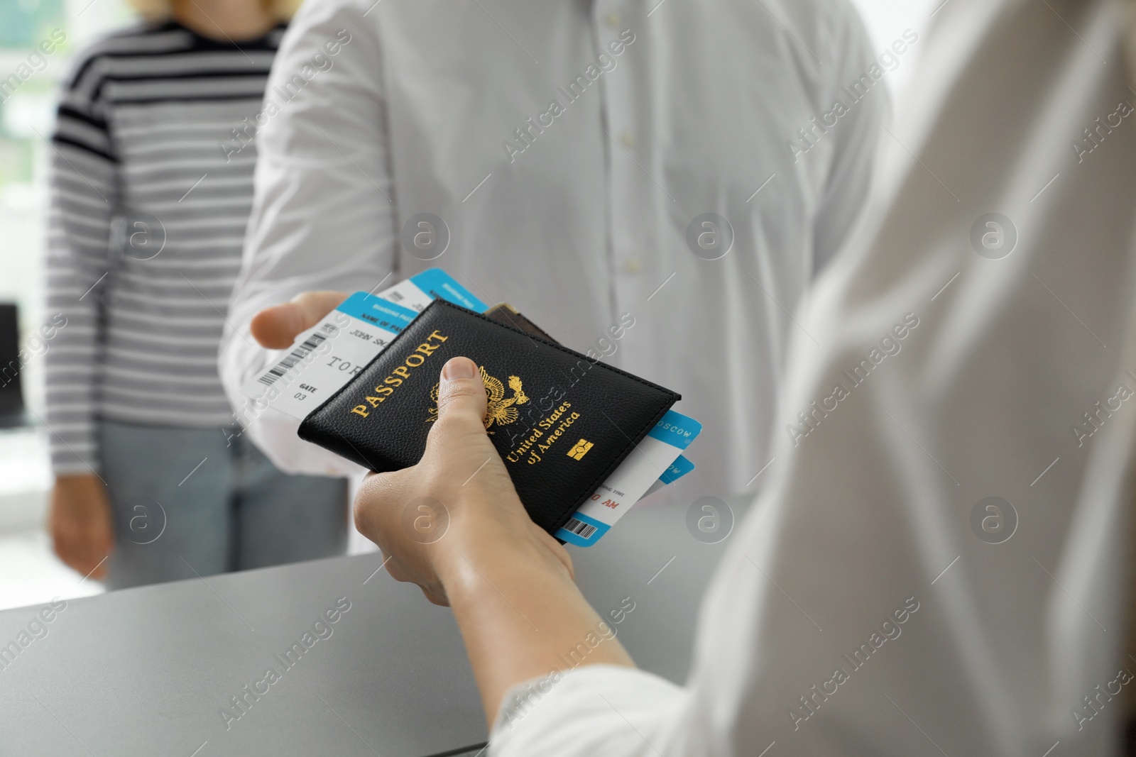 Photo of Agent giving passports and tickets to man at check-in desk in airport, closeup