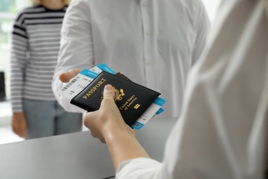 Agent giving passports and tickets to man at check-in desk in airport, closeup