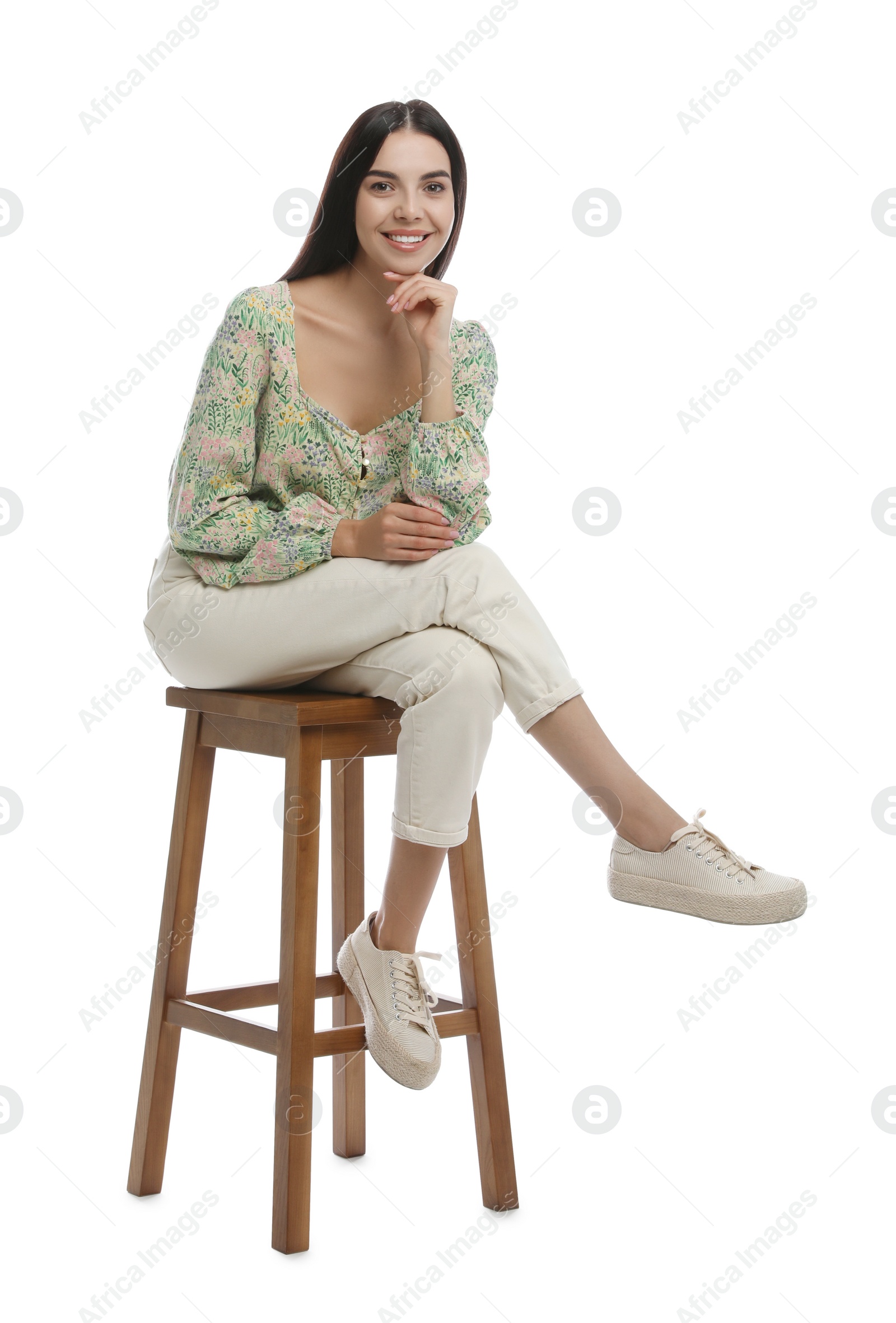 Photo of Beautiful young woman sitting on stool against white background