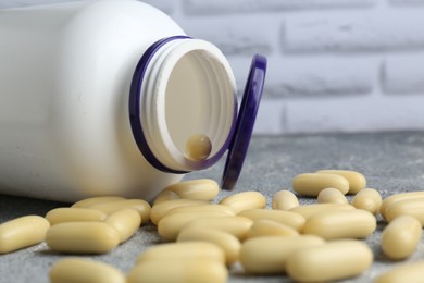 Photo of White medical bottle and pills on light gray table, closeup