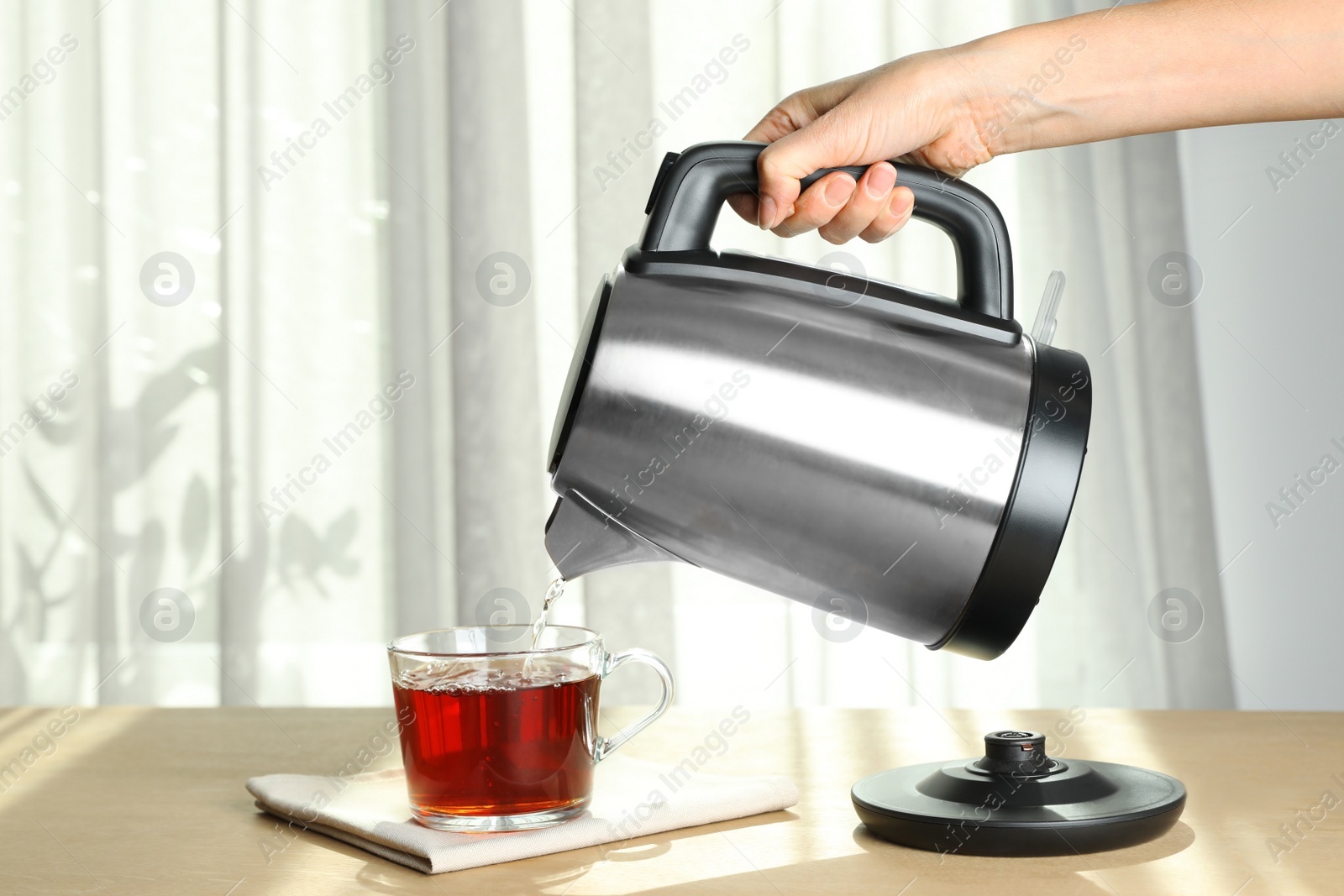 Photo of Woman making tea at wooden table indoors, closeup