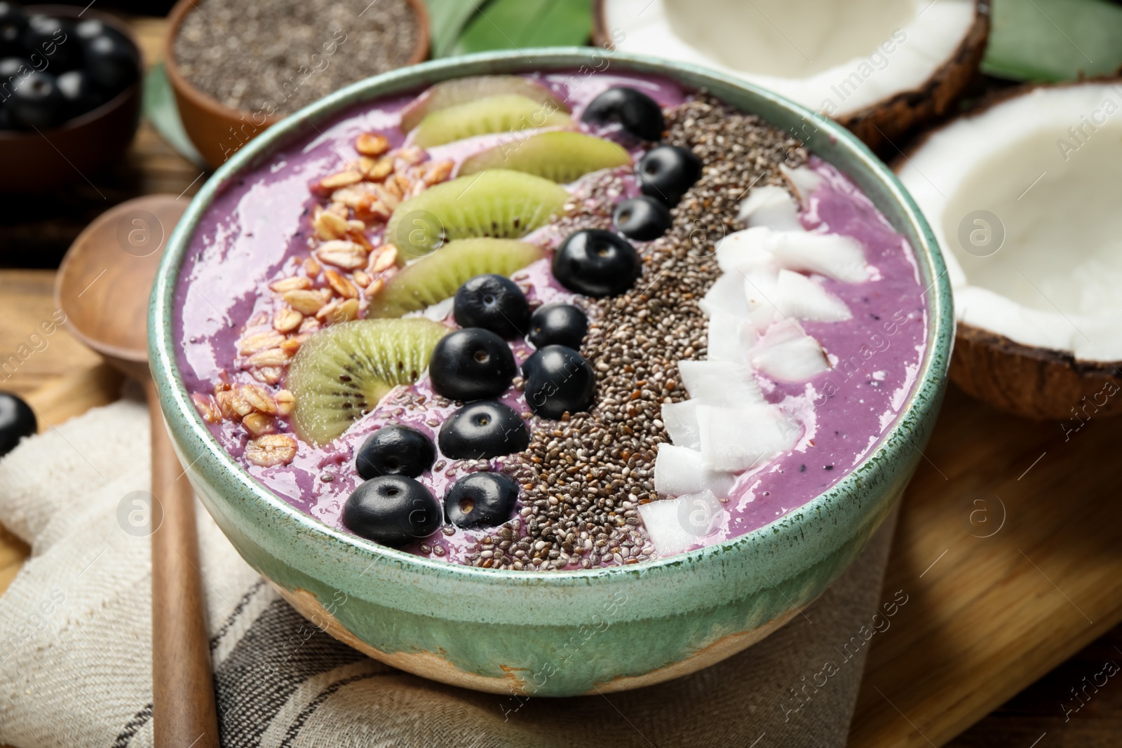 Photo of Delicious acai smoothie with fruits and chia seeds in bowl on table, closeup