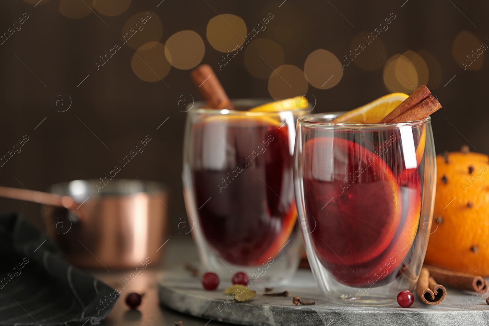 Photo of Glasses of tasty mulled wine on table against festive lights