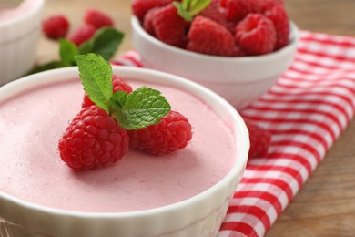 Photo of Delicious raspberry mousse with mint on wooden table, closeup
