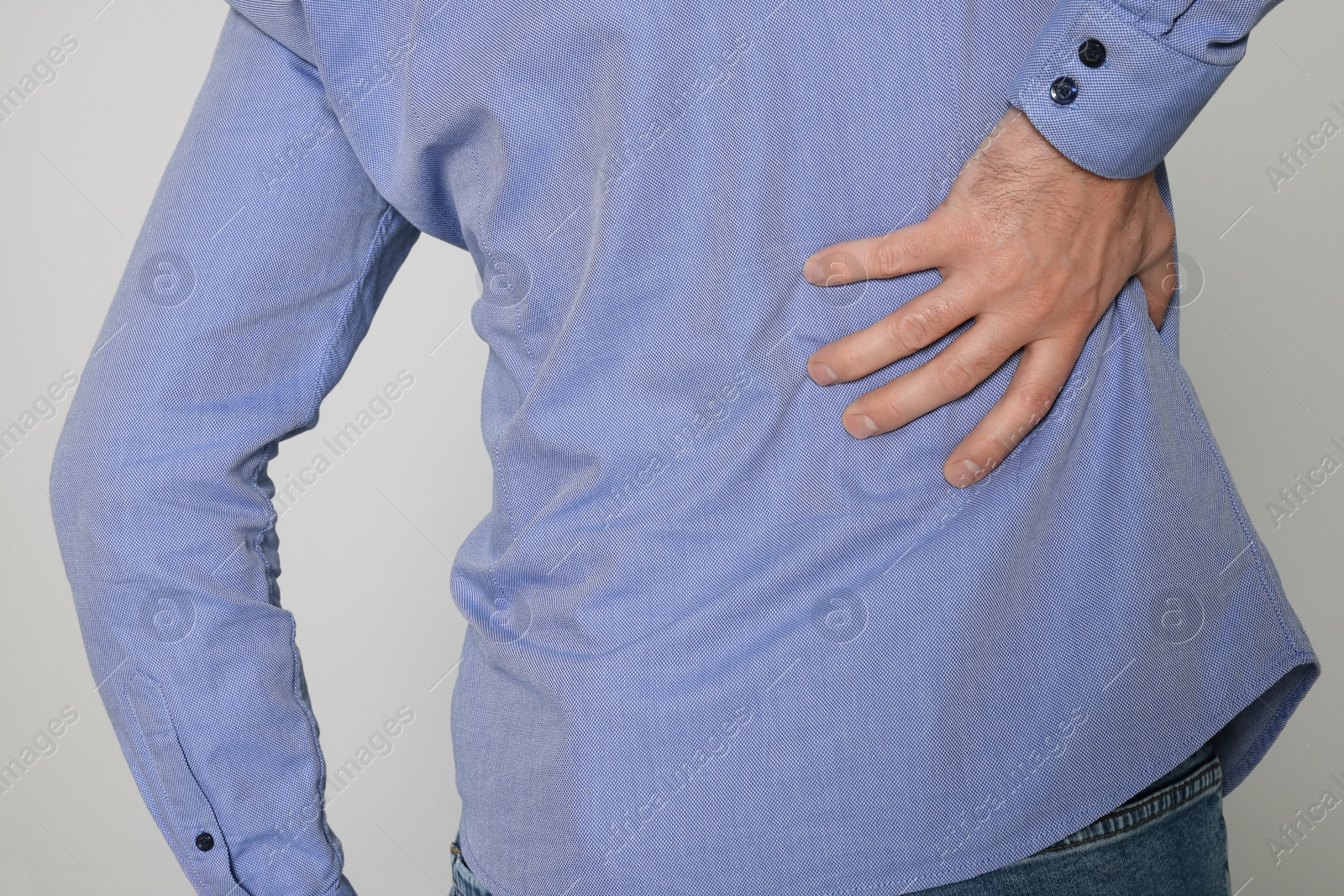 Photo of Man suffering from pain in back on light background, closeup. Arthritis symptoms