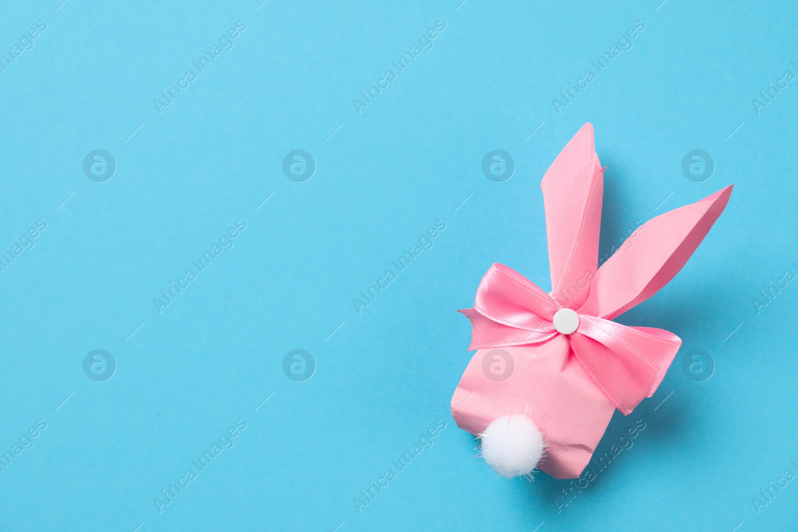 Photo of Creative Easter bunny gift bag on color background, top view with space for text