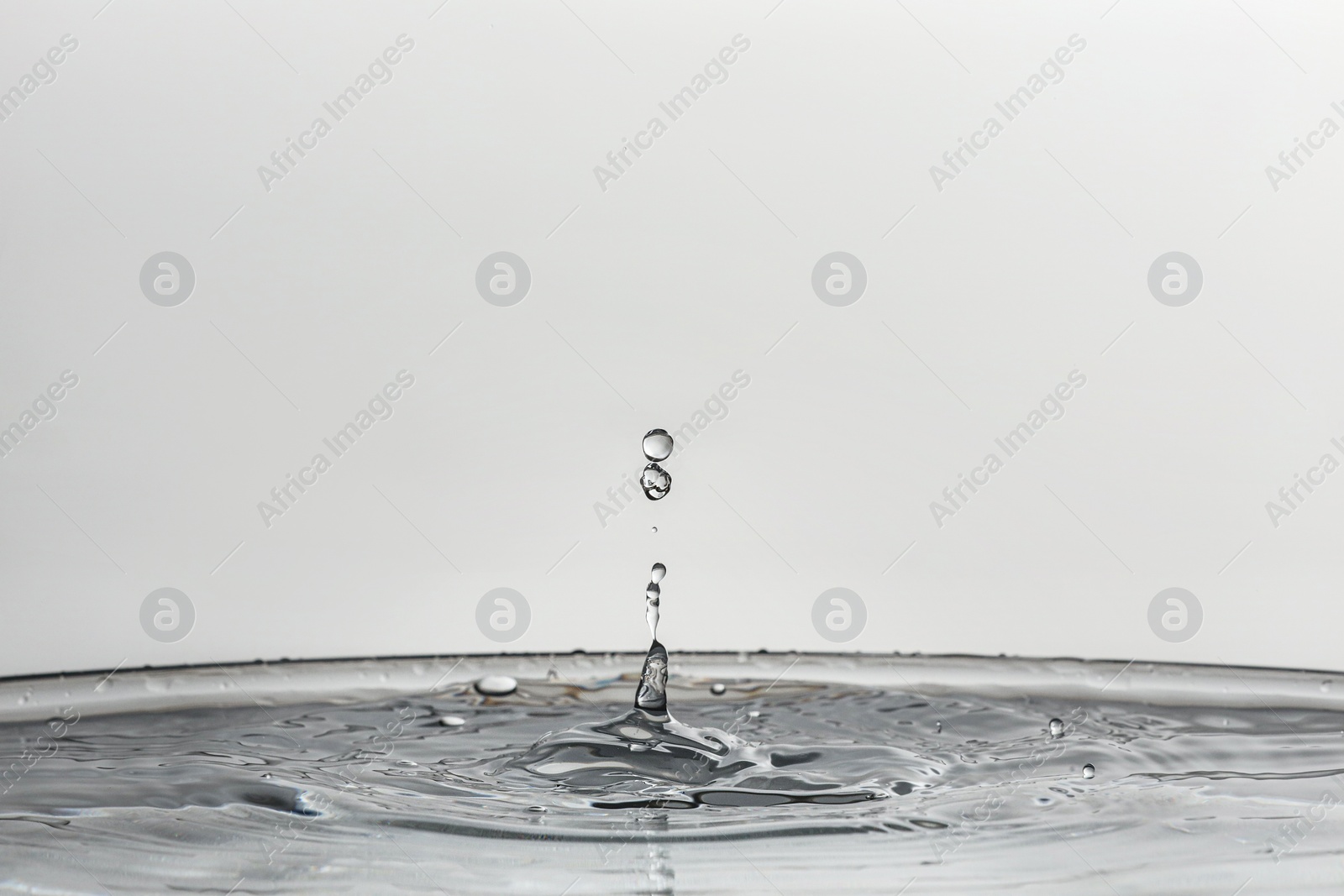 Photo of Splash of clear water with drops on light background, closeup