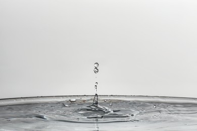 Photo of Splash of clear water with drops on light background, closeup