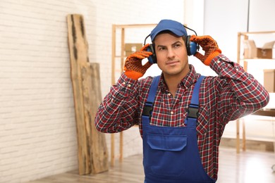 Photo of Worker wearing safety headphones indoors, space for text. Hearing protection device
