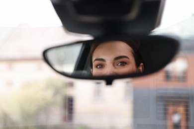 Woman driving her car, reflection in rear view mirror