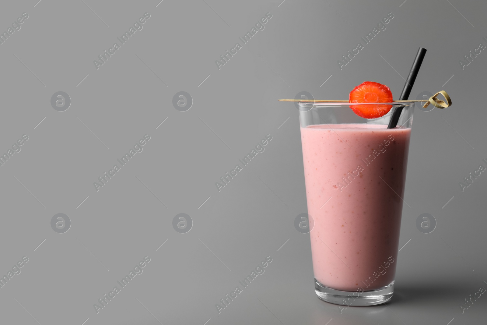 Photo of Glass with delicious berry smoothie on grey background. Space for text