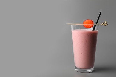 Photo of Glass with delicious berry smoothie on grey background. Space for text