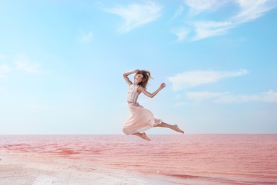 Beautiful woman posing near pink lake on sunny day