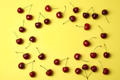 Flat lay composition with sweet cherries on yellow background. Space for text