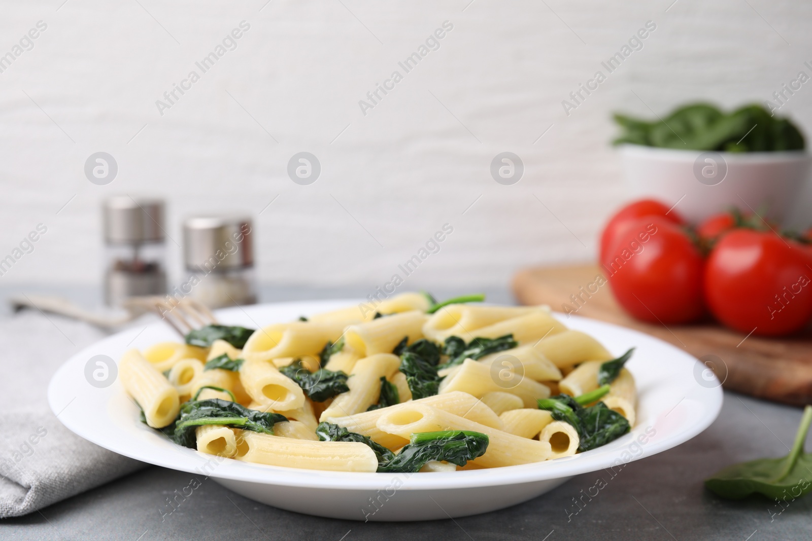 Photo of Tasty pasta with spinach on grey table, closeup