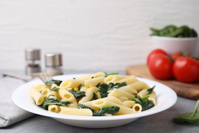 Photo of Tasty pasta with spinach on grey table, closeup