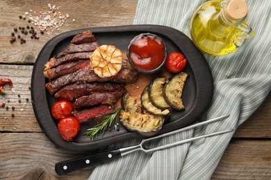 Photo of Delicious grilled beef with vegetables, tomato sauce and spices on wooden table, top view