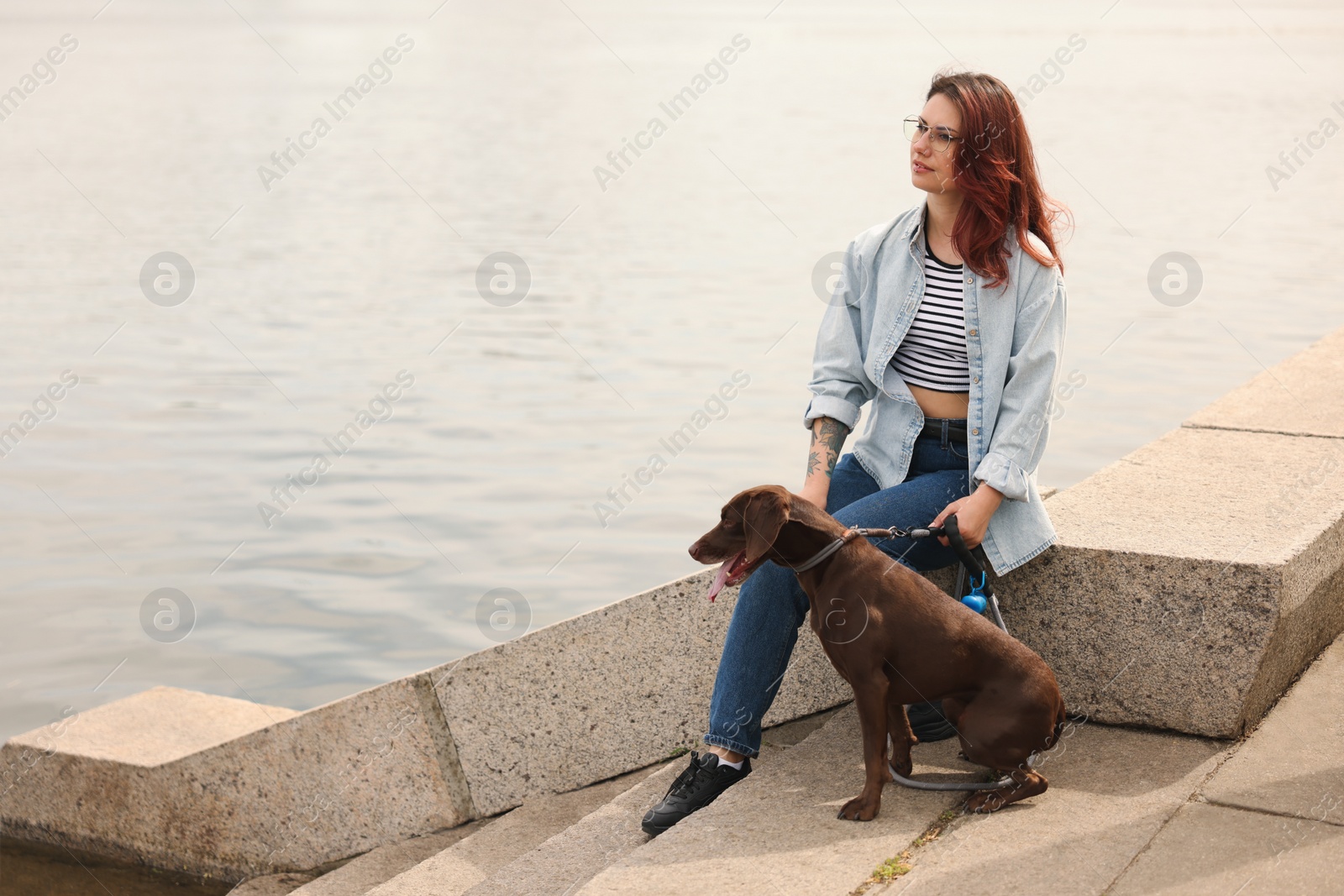 Photo of Woman with her cute German Shorthaired Pointer dog outdoors, space for text