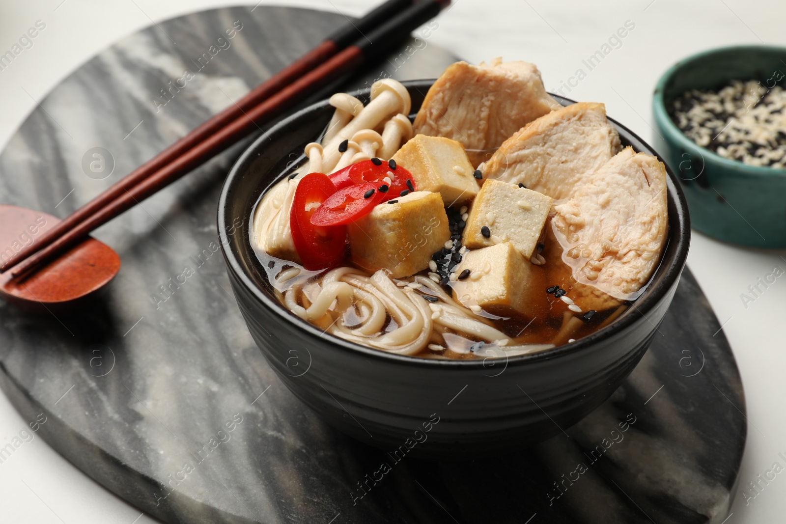 Photo of Delicious ramen served on white table, closeup. Noodle soup