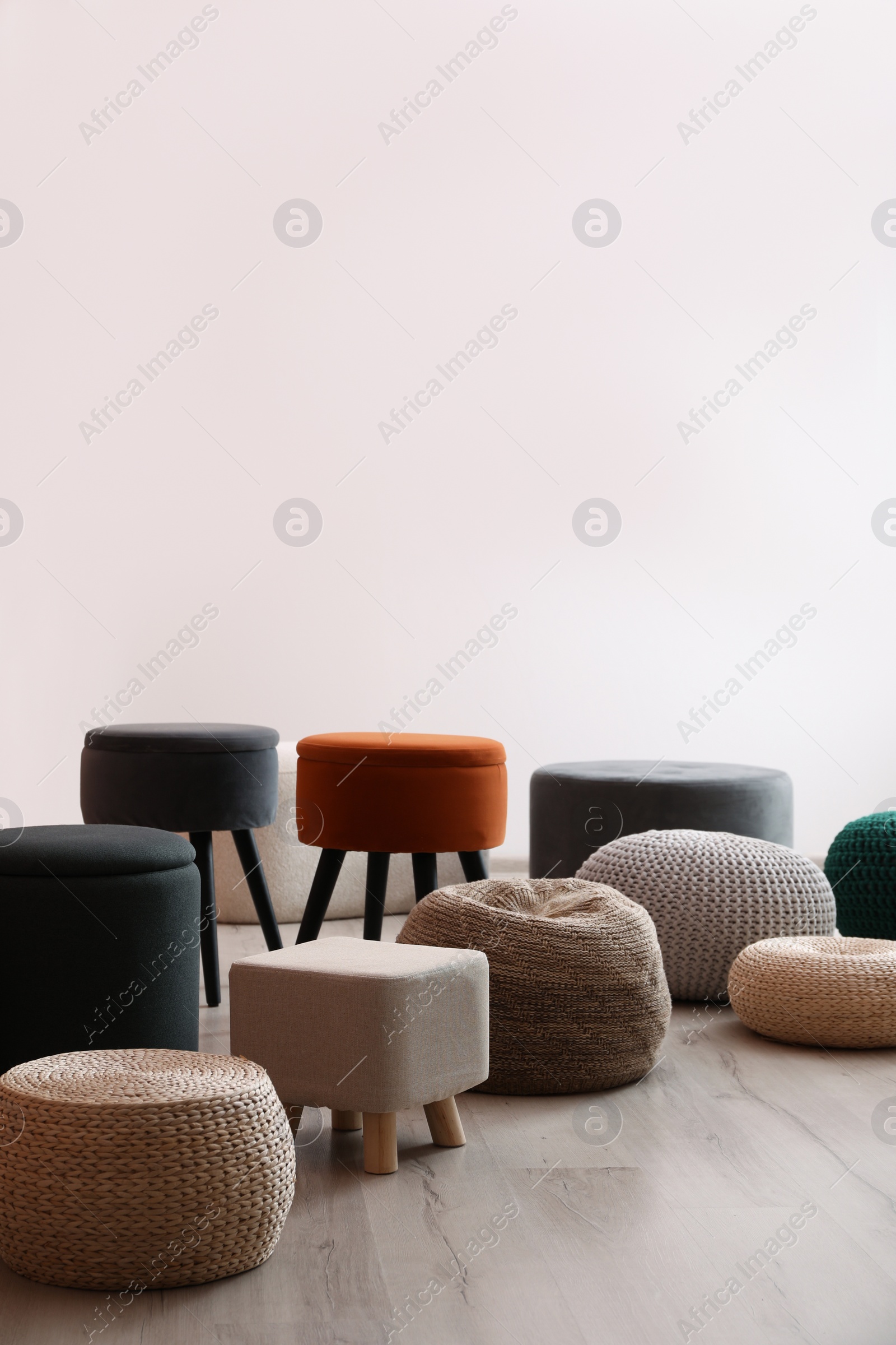 Photo of Different stylish poufs and ottomans in room, space for text