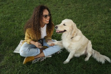 Photo of Young African-American woman and her Golden Retriever dog on green grass