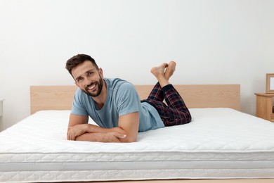 Happy man on bed with comfortable mattress at home