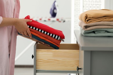Photo of Woman putting clean clothes into drawer at home, closeup