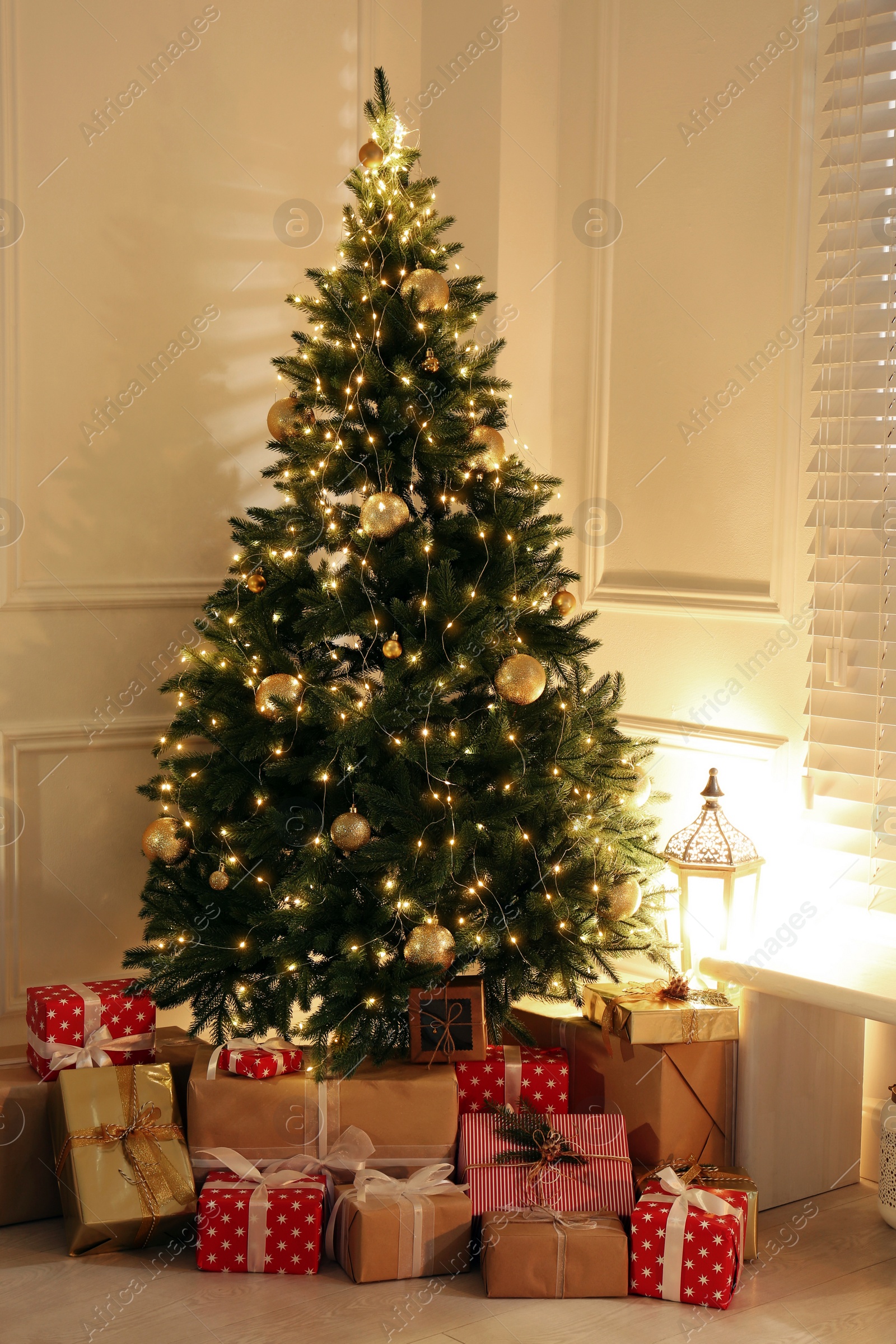 Photo of Gift boxes under Christmas tree with fairy lights indoors