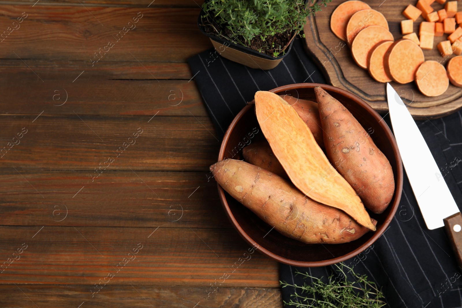 Photo of Flat lay composition with cut and whole sweet potatoes on wooden table. Space for text