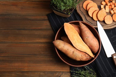 Photo of Flat lay composition with cut and whole sweet potatoes on wooden table. Space for text