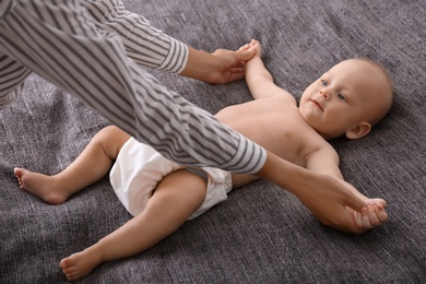 Photo of Young woman massaging cute little baby on blanket