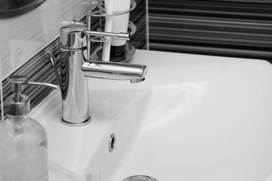 Image of Clean white sink with shiny water tap in bathroom