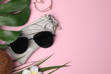 Stylish sunglasses with bag on pink background, flat lay. Space for text