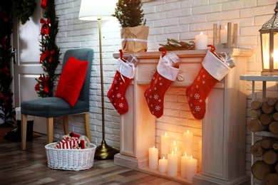 Red Christmas stockings with gifts on decorative fireplace in festive room interior