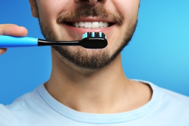 Photo of Young man with toothbrush on color background, closeup